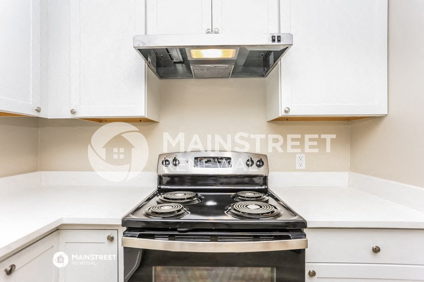 a kitchen with white cabinets and a stove and a microwave