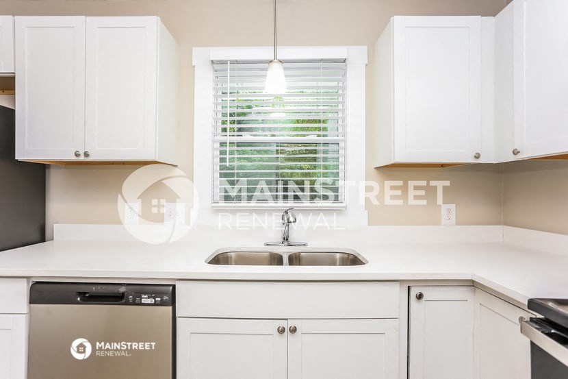 a kitchen with white cabinets and a sink and a window