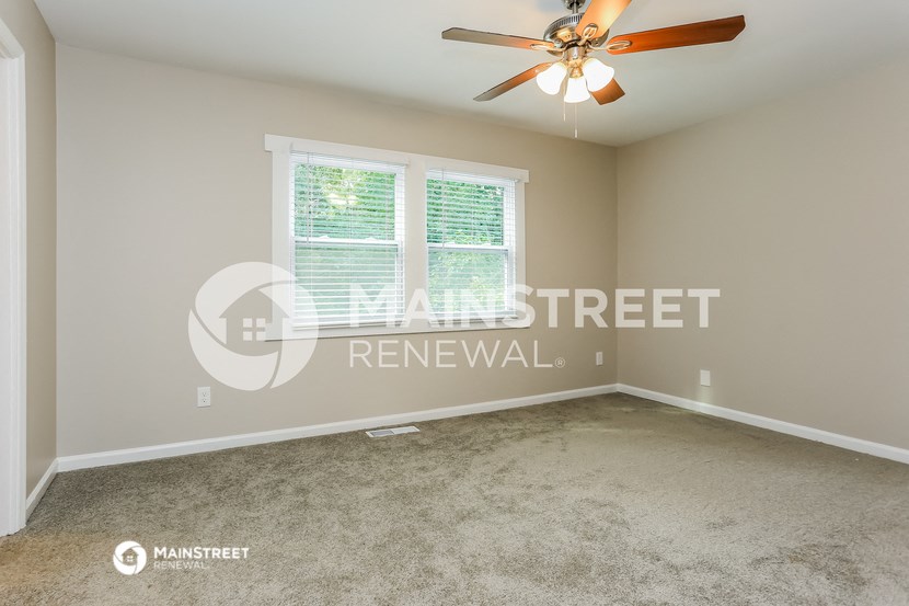 a bedroom with a large window and a ceiling fan