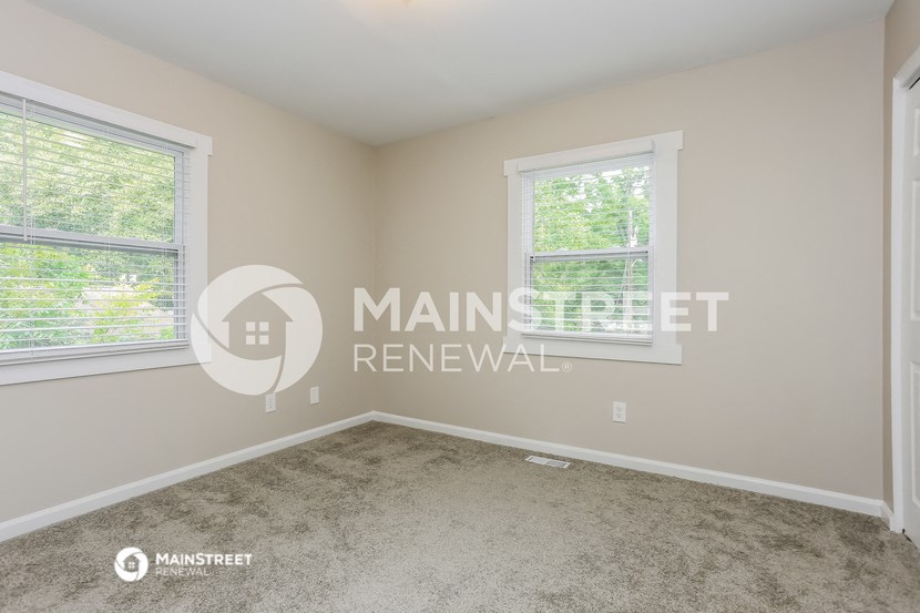 a bedroom with a carpeted floor and two windows