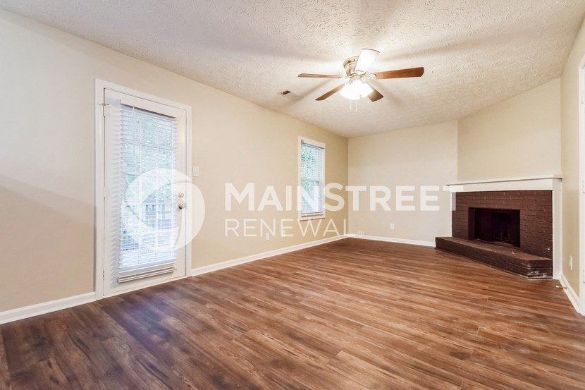 an empty living room with wood floors and a fireplace