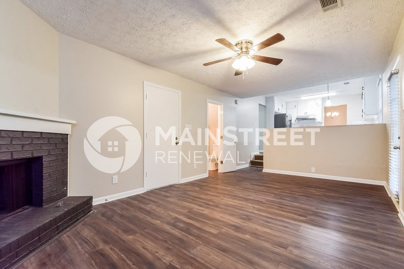 a living room with a fireplace and a ceiling fan