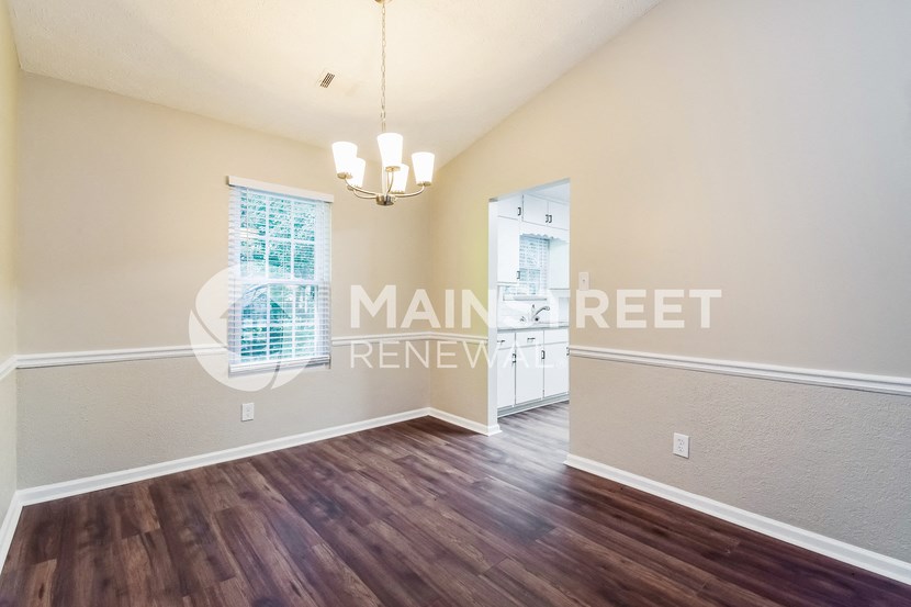 an empty living room with hardwood flooring and a door to the bathroom