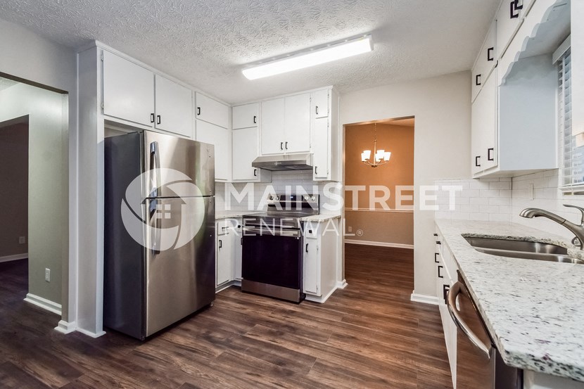 a renovated kitchen with white cabinets and a stainless steel refrigerator