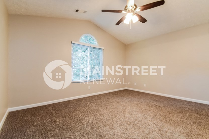 an empty living room with a window and a ceiling fan