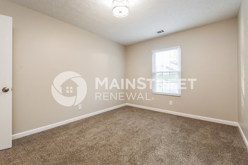 an empty living room with carpet and a window