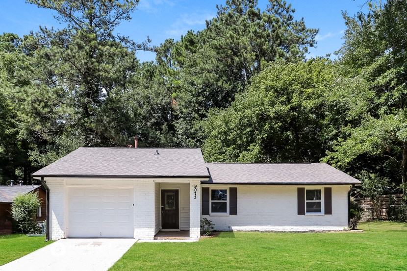 a small white house with a lawn and trees