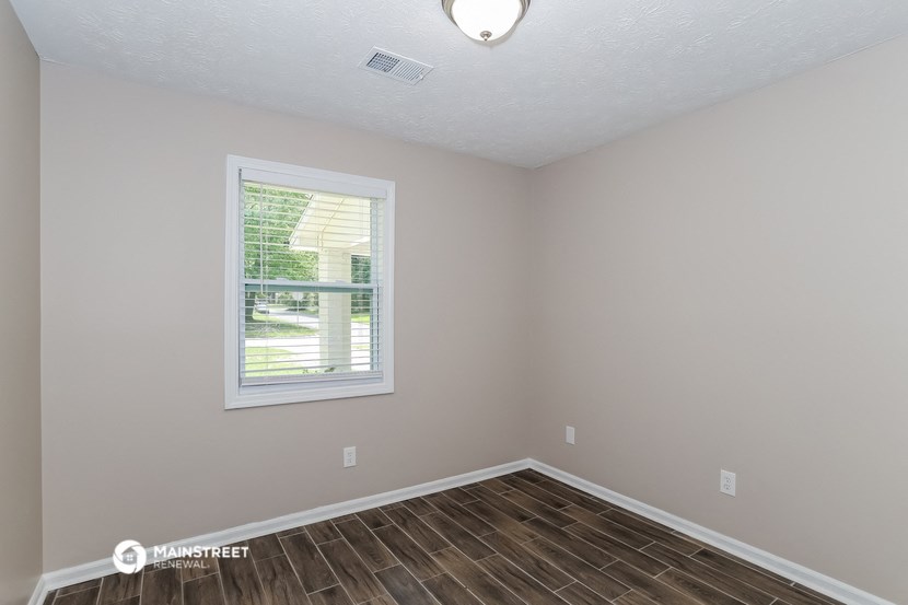 the living room of a house with a window and wooden floors