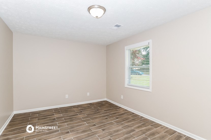 the spacious living room with wood flooring and a window