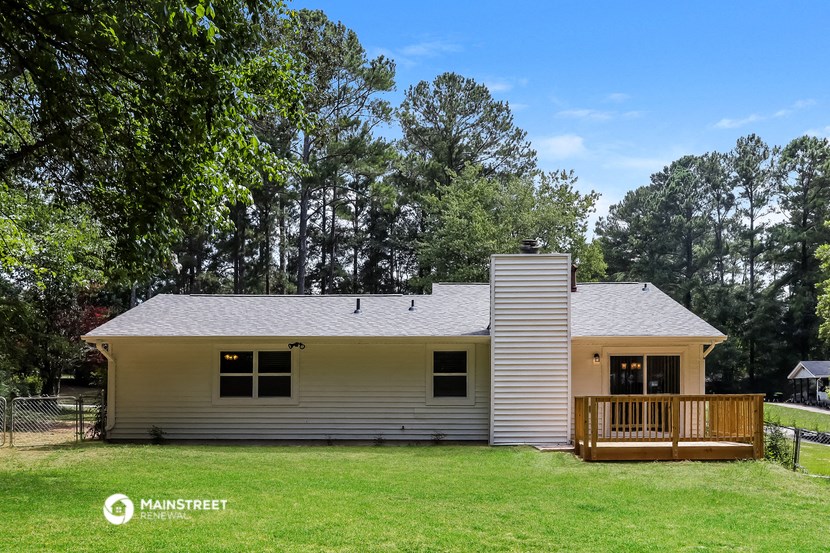 a small yellow and with a deck and trees