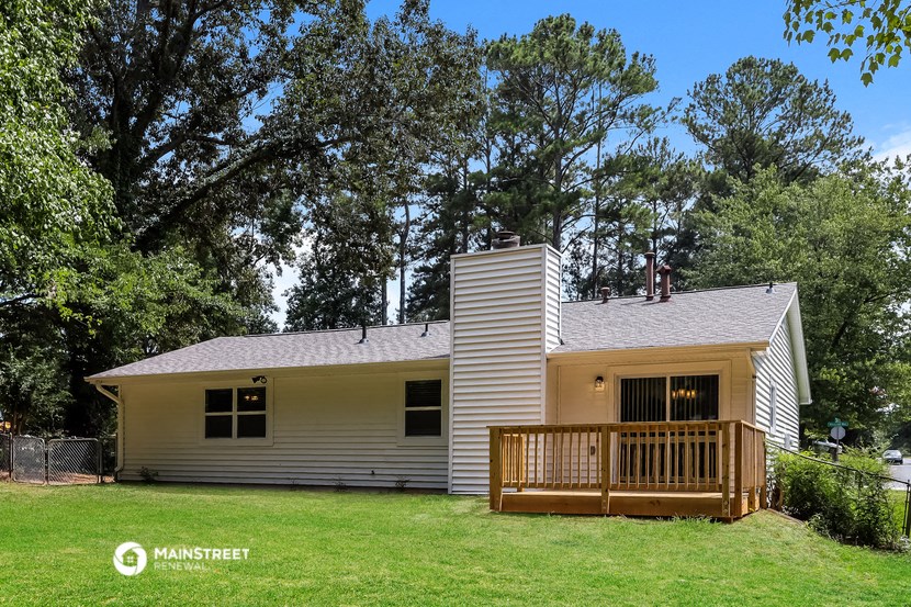 a small white house with a deck on a lawn