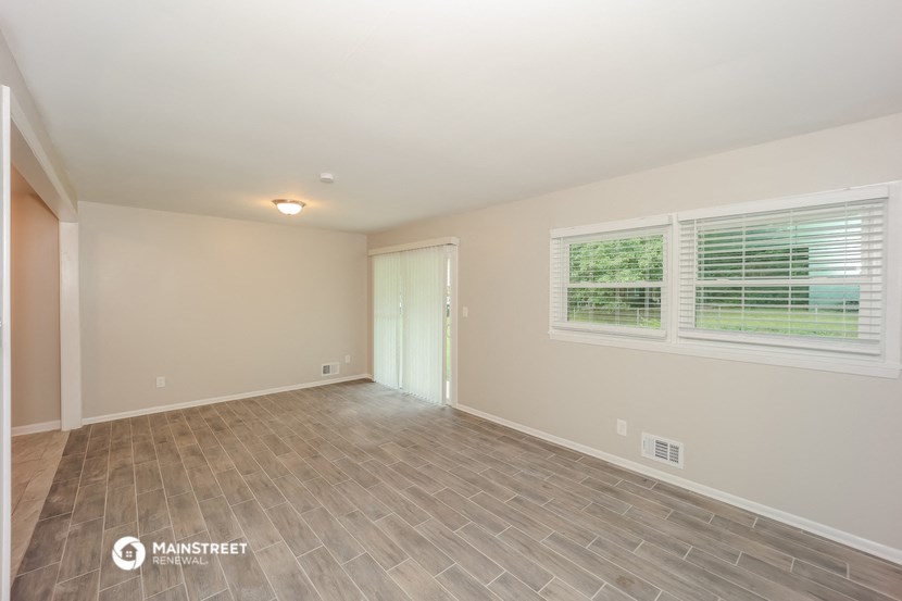 the spacious living room with vinyl flooring and a large window