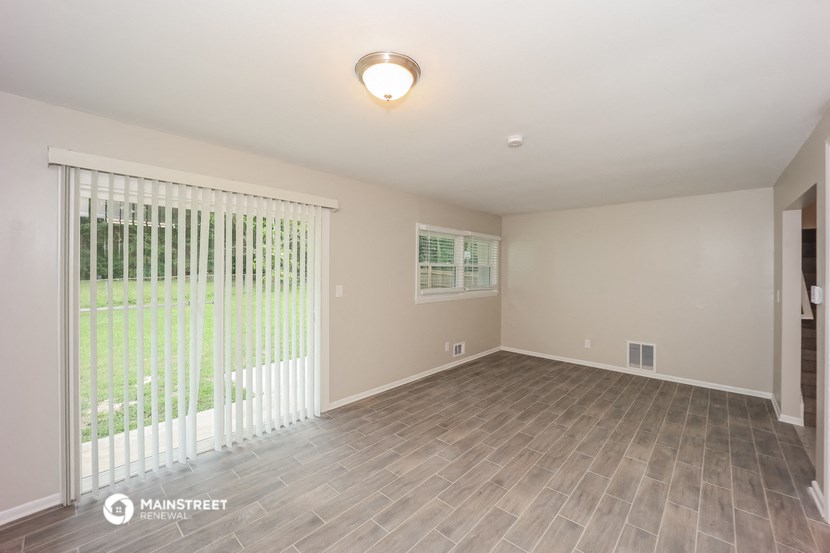 the spacious living room with wood flooring and a large window