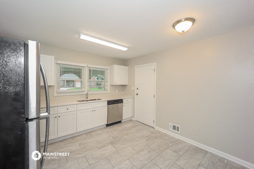 a kitchen with white cabinets and a stainless steel refrigerator