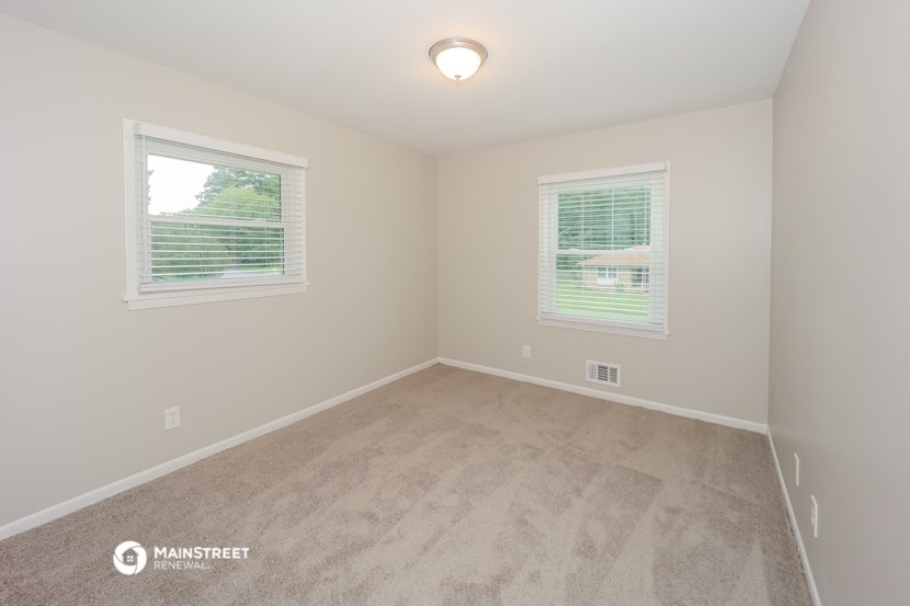 a bedroom with a carpeted floor and two windows