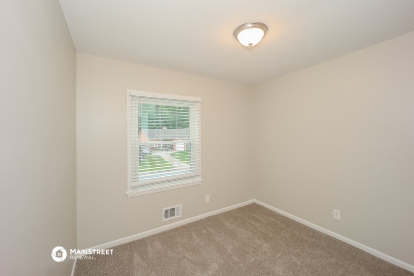 a spacious bedroom with a window and carpeted flooring