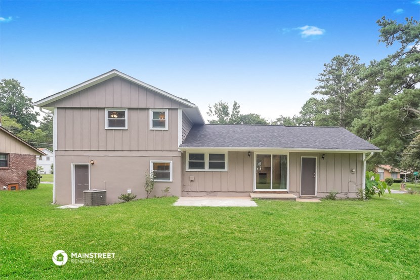 a gray house with a green lawn and trees