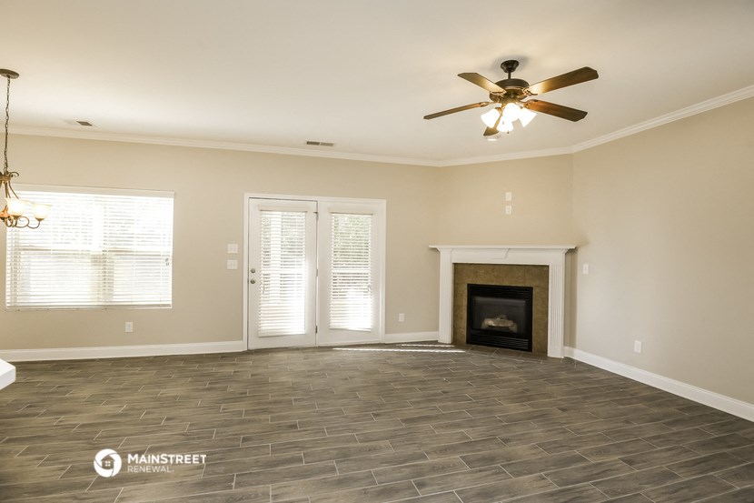 the living room with a fireplace and a ceiling fan
