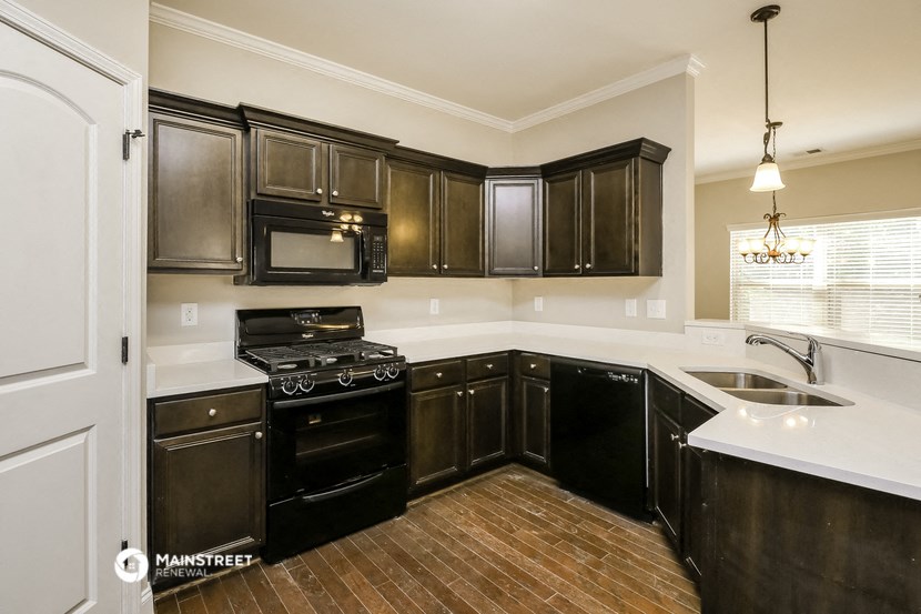 an empty kitchen with black appliances and dark cabinets
