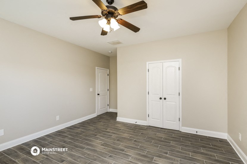 the spacious living room with tile flooring and a ceiling fan