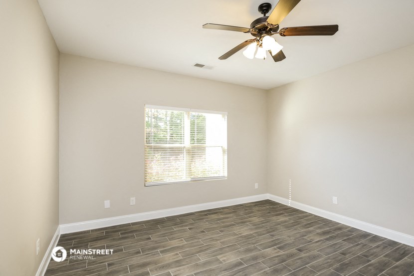 an empty living room with a ceiling fan and a window