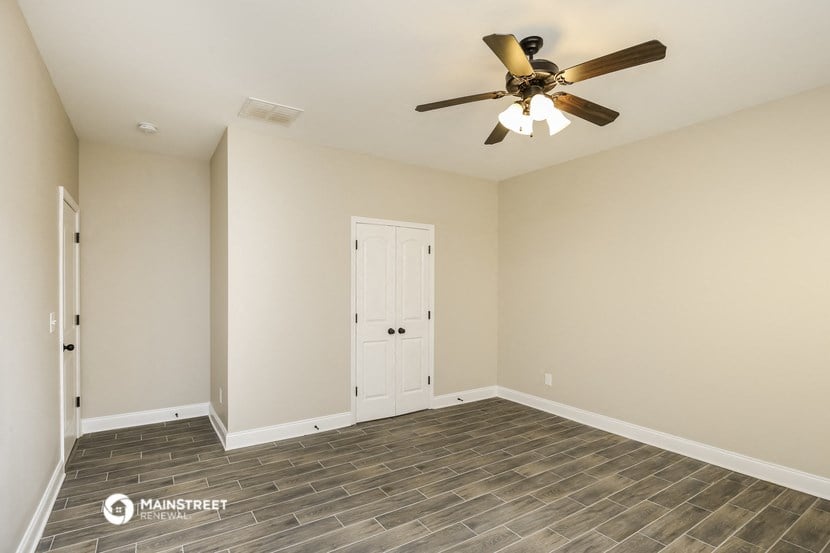 the spacious living room with tile flooring and a ceiling fan