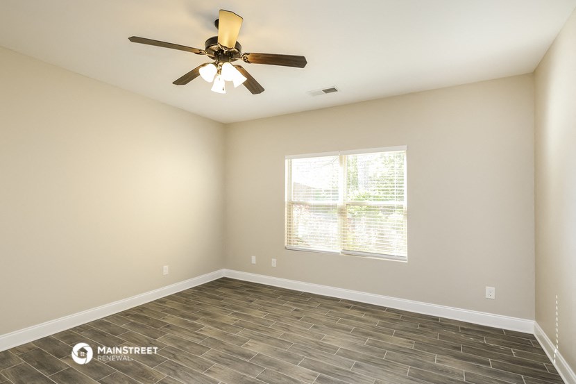 the spacious living room with wood floors and a ceiling fan