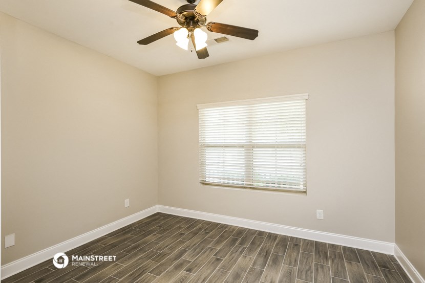 the spacious living room with wood flooring and a ceiling fan
