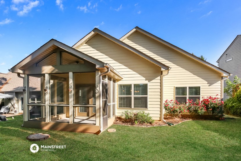 a small yellow house with a porch and a lawn