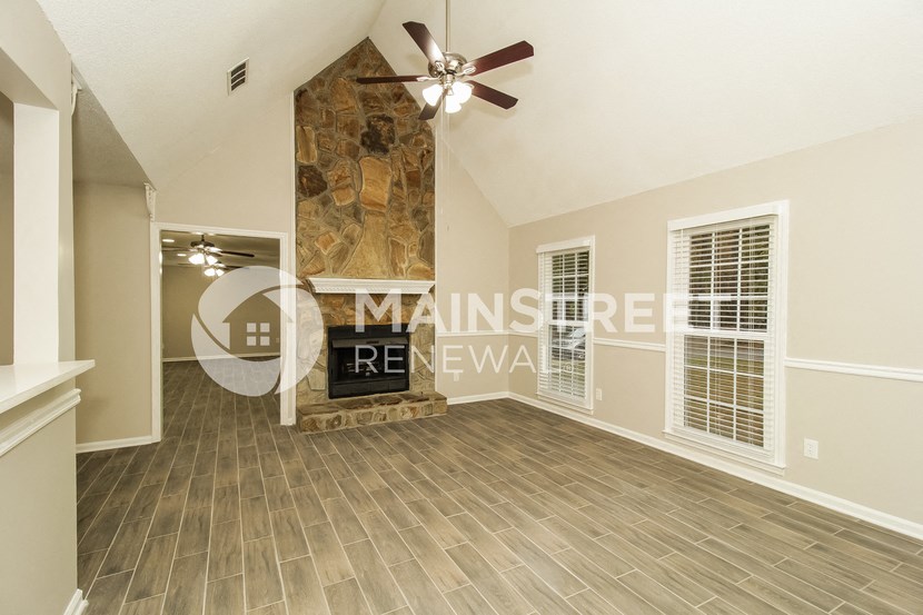 a large living room with a stone fireplace and wood floors