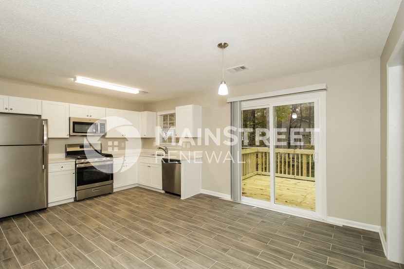 a kitchen with stainless steel appliances and a sliding glass door to a deck