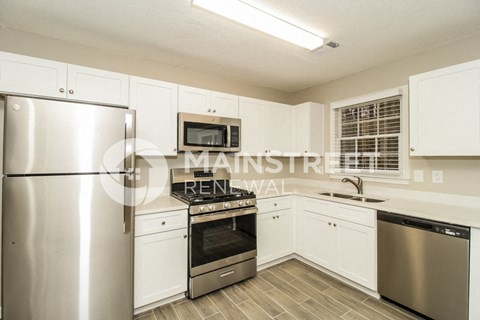 a kitchen with white cabinets and stainless steel appliances