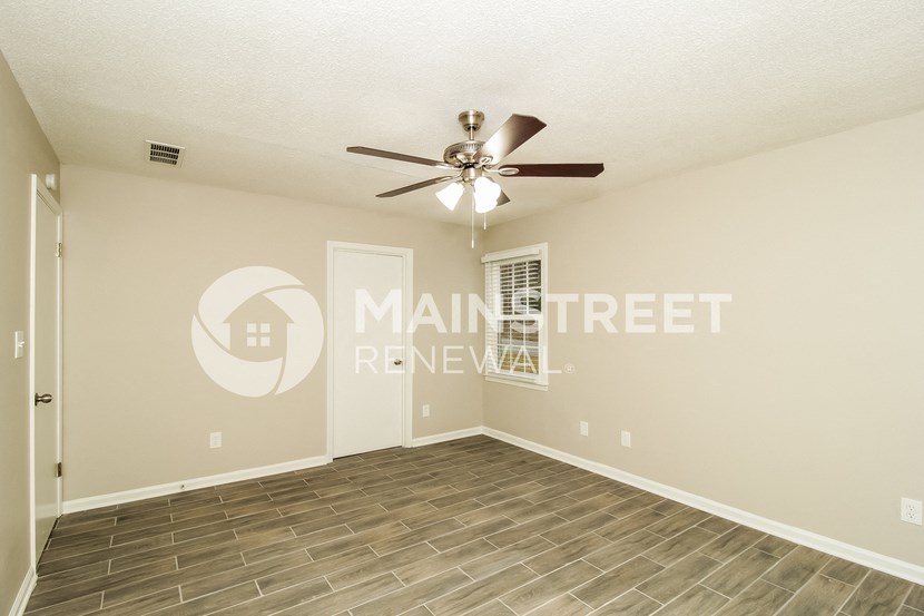 a living room with wood floors and a ceiling fan