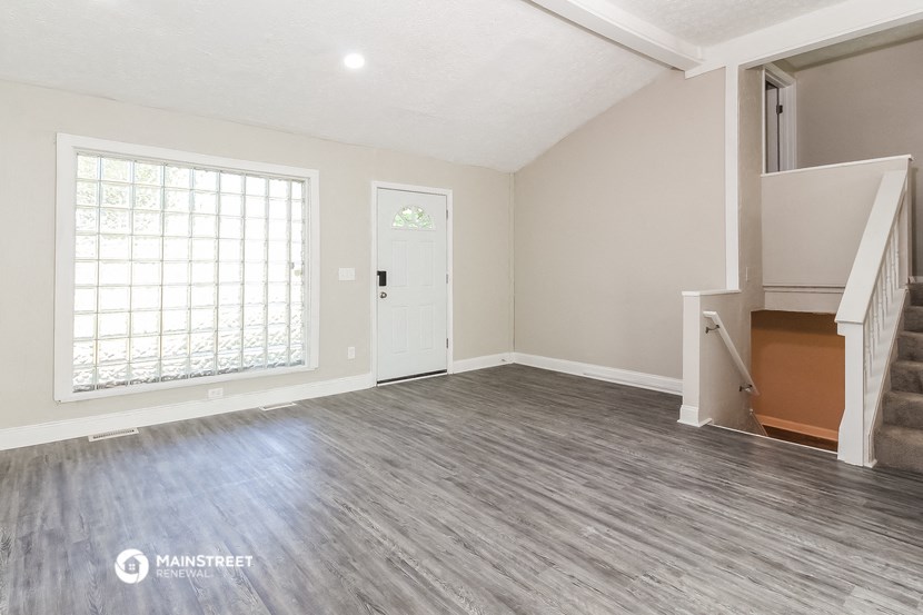 an empty living room with a staircase and a window