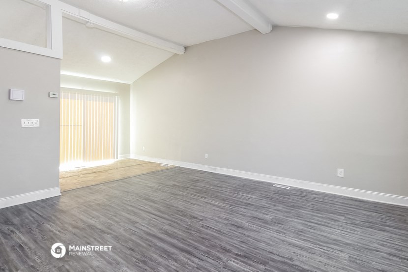 an empty living room with wood flooring and white walls