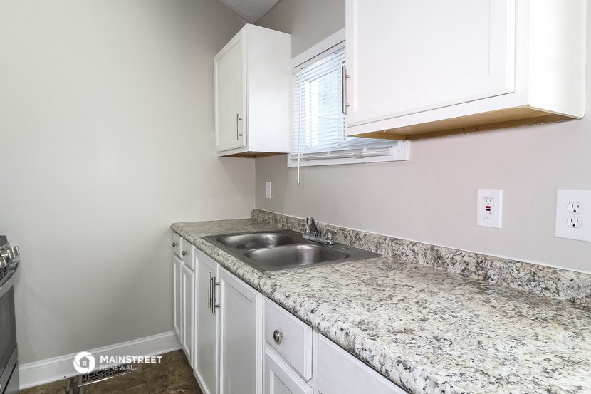 a kitchen with white cabinets and granite counter tops and a sink