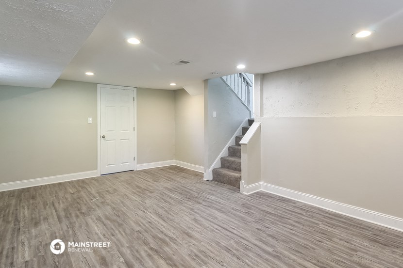 the basement of a new home with white walls and a staircase
