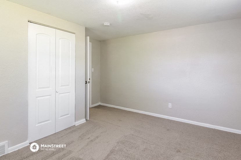 a bedroom with white doors and carpet and a door to a closet