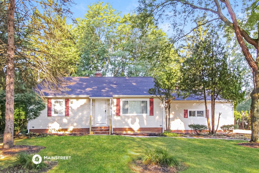 a small white house with red shutters and trees