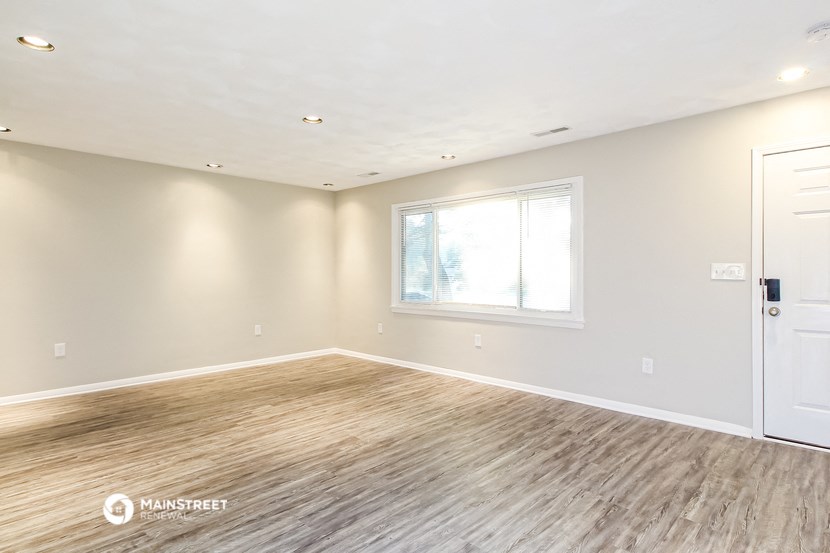 the living room of a new home with wood flooring and a window