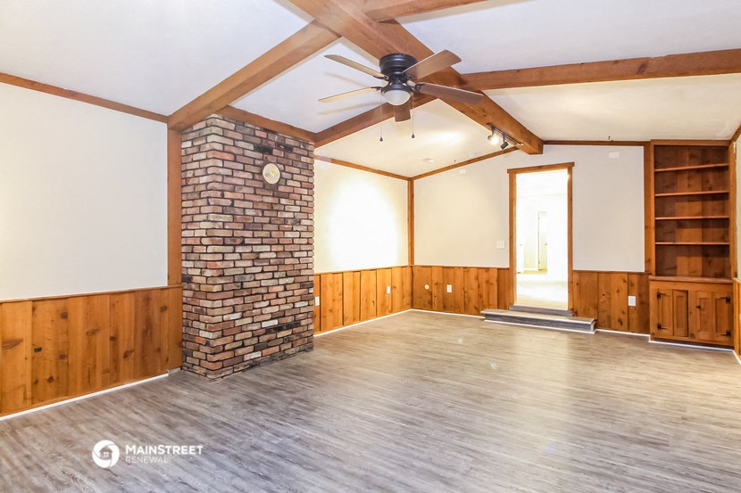 an empty living room with wood floors and a brick fireplace