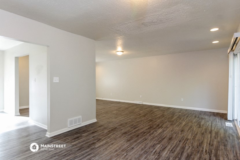 an empty living room with wood flooring and white walls