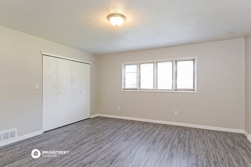 the spacious living room with wood flooring and a window