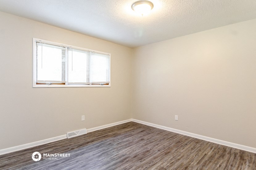 the spacious living room with wood flooring and a window
