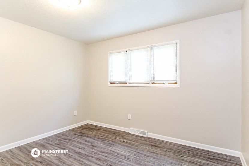 the spacious living room with wood flooring and a window