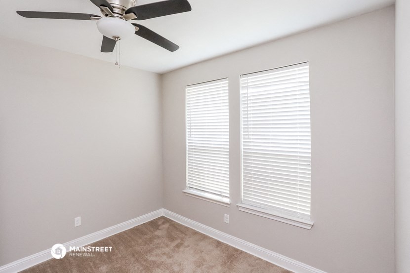 a bedroom with a ceiling fan and two windows