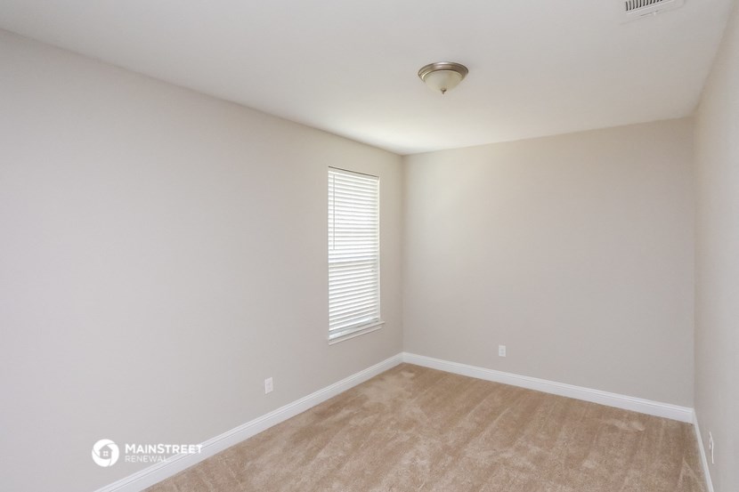 an empty room with a window and a ceiling fan