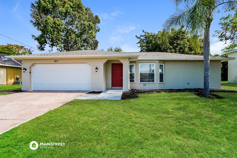 a white house with a red door and a lawn