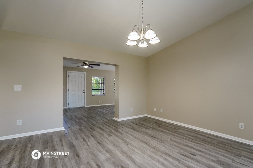 the spacious living room with vinyl flooring and a ceiling fan