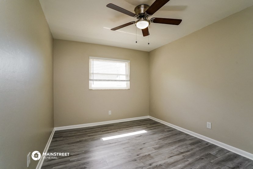 an empty room with a ceiling fan and a window